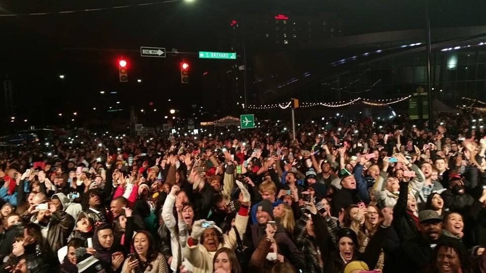 A crowd of thousands at an outdoor night concert, lit from the stage