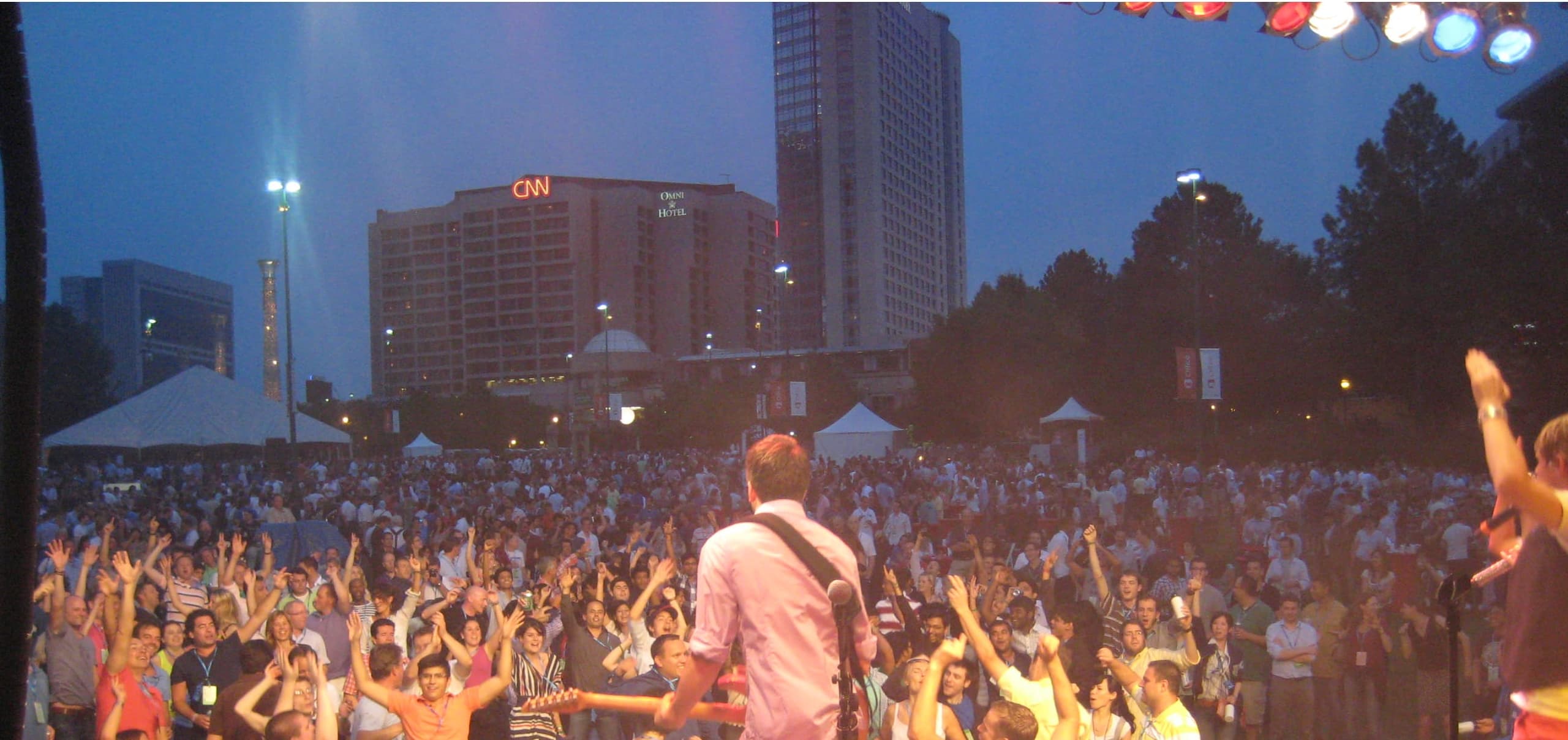 An outdoor crowd at dusk, with the stage on the right and the Atlanta skyline behind